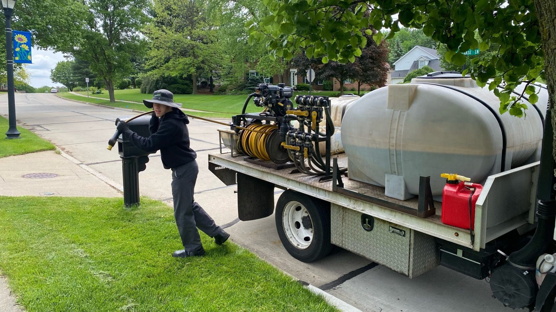 Greener Grass lawn care professional in Canton, OH, retrieving a hose from the service truck to begin expertly delivering organic lawn care services, ensuring the health and vitality of local lawns in the Canton community.